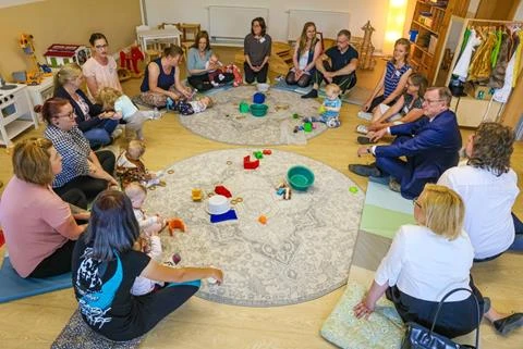Kinder und Erwachsene sitzen im Kreis auf dem Boden